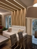Boiserie in legno chiaro dietro un divano in pelle bianco all'interno di un soggiorno moderno_1