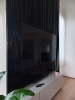 Vista laterale parete boiserie di colore nero all'interno di un soggiorno di un mansardato con incastonato un televisore a schermo piatto spento_1