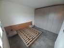 Panoramica camera da letto con all'interno la struttura del letto contenitore e un armadio a muro di colore grigio_1
